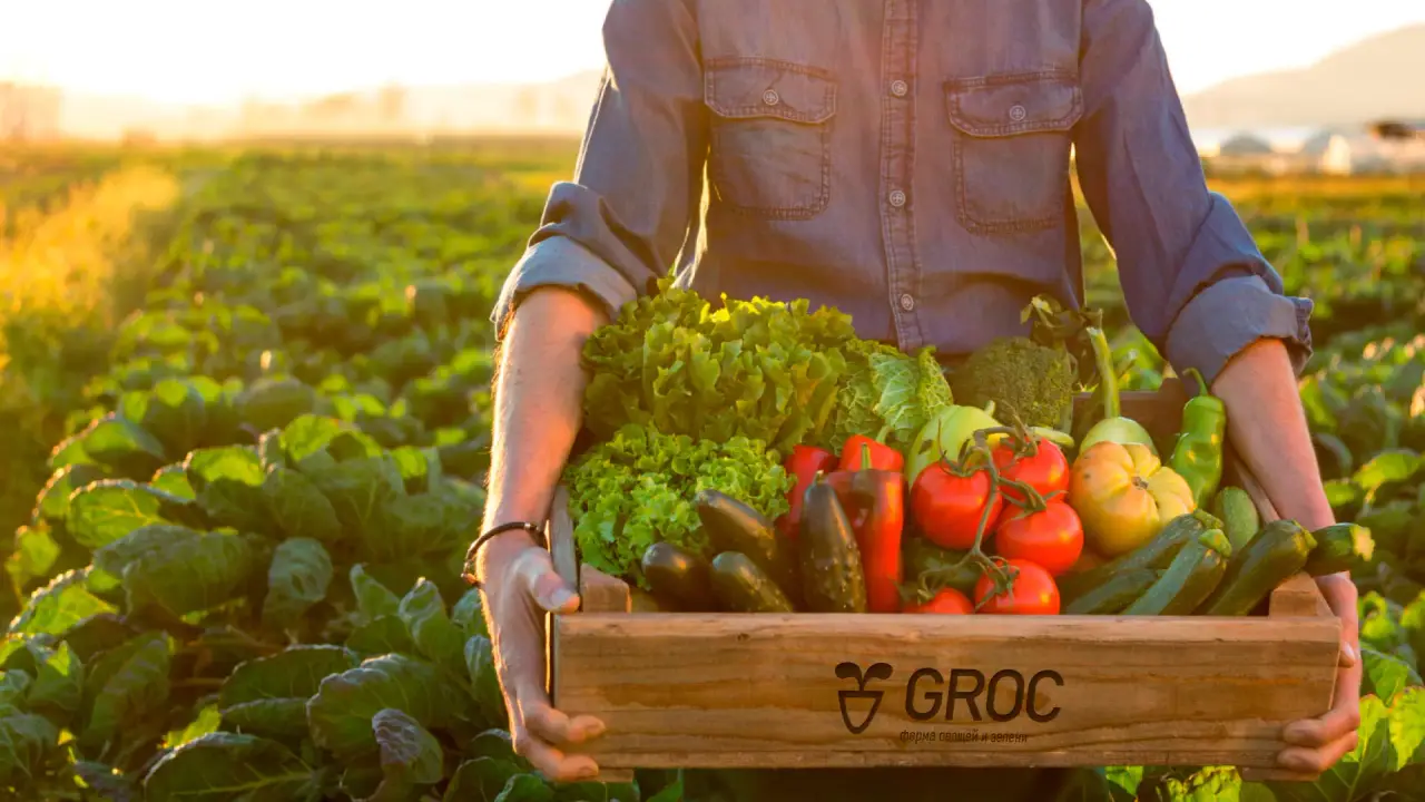 A farmer with a wooden crate branded with Groc logo.