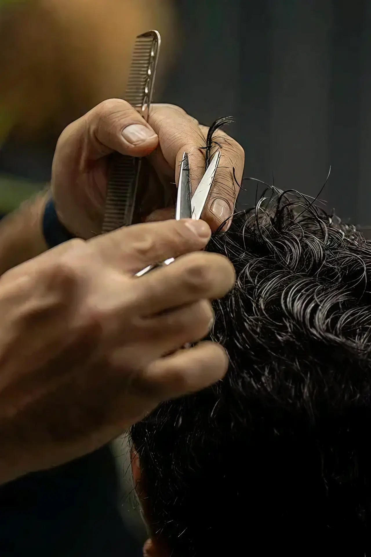 A close-up of client's hair with a barber cutting the hair.