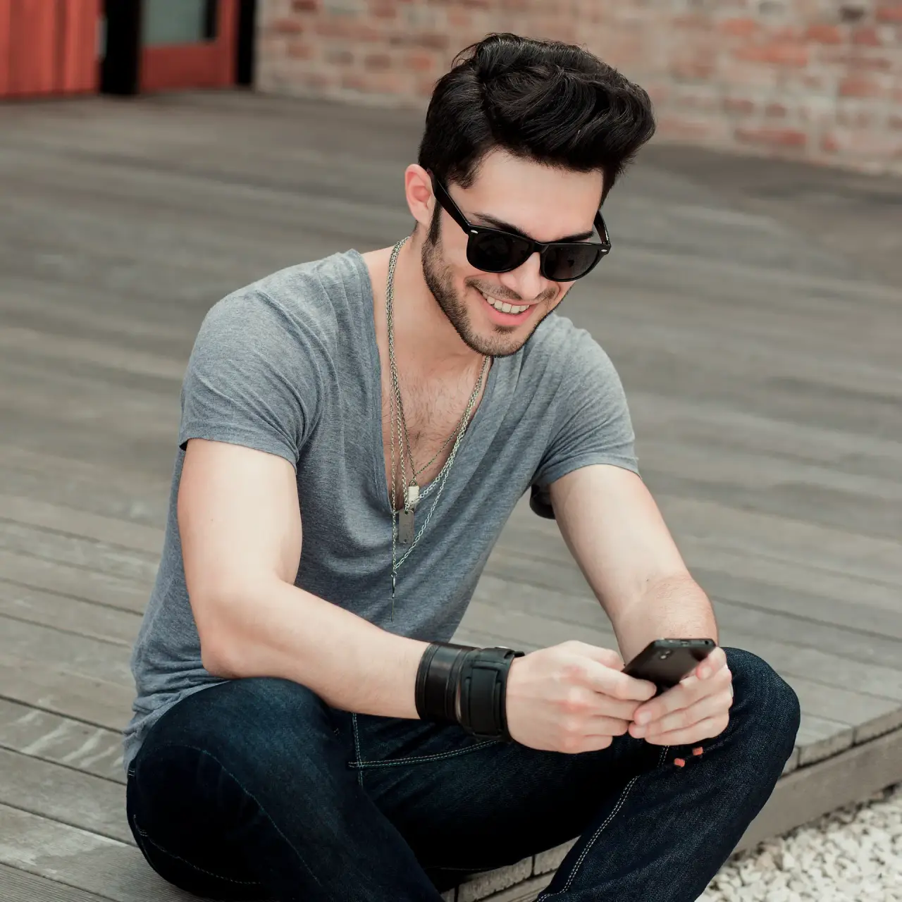 A smiling man scrolling through a phone.